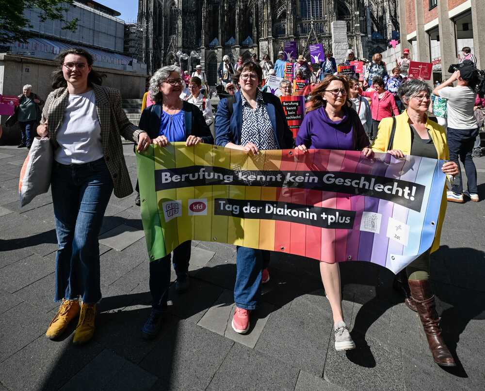 TagderDiakoninplus_c_Steinbrecht_KNA.jpg Gruppe von Frauen, die ein Banner zum Tag der Diakonin 2025 halten