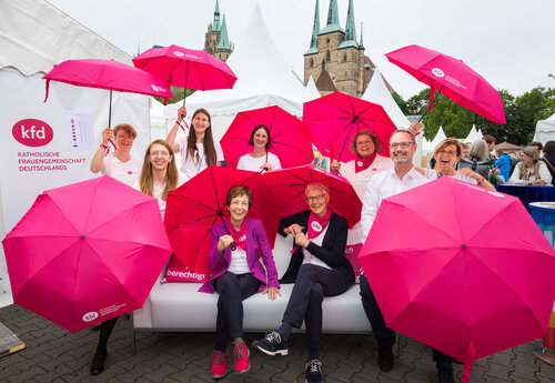 Viele Frauen mit purpurfarbenen Schirmen auf einem Sofa